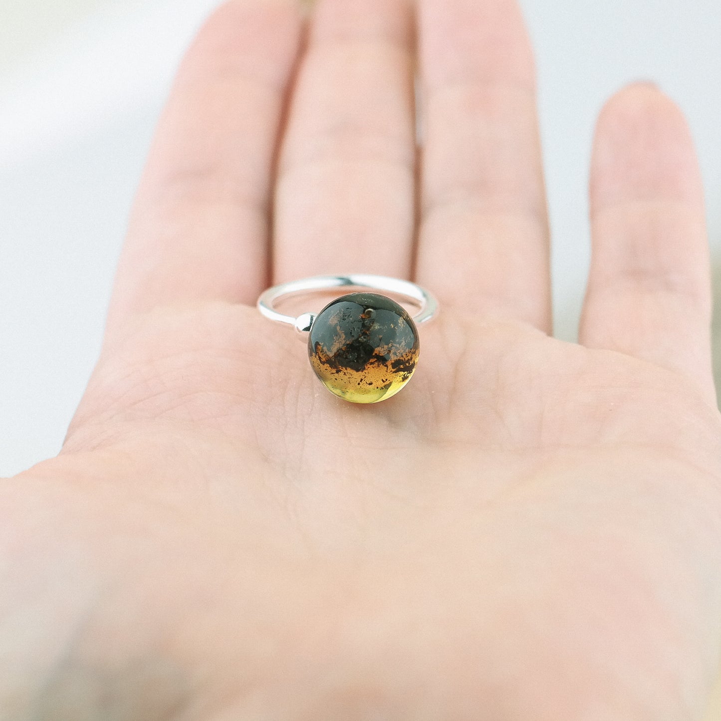 Adjustable silver ring with natural green amber bead